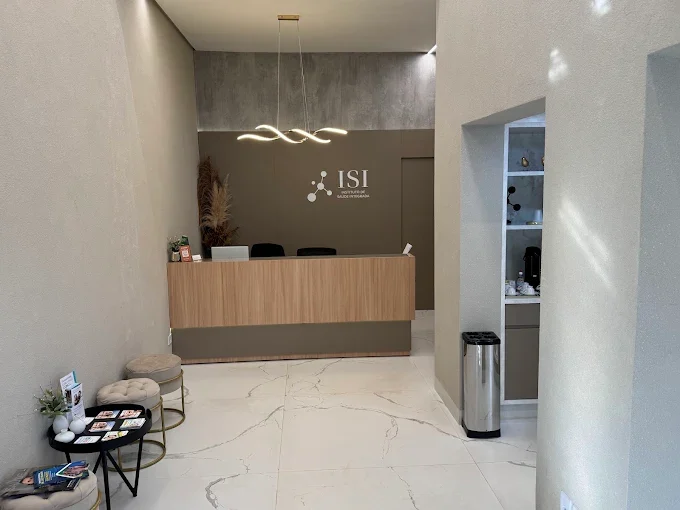 Recepção com balcão em madeira clara, piso de mármore e luminária pendente